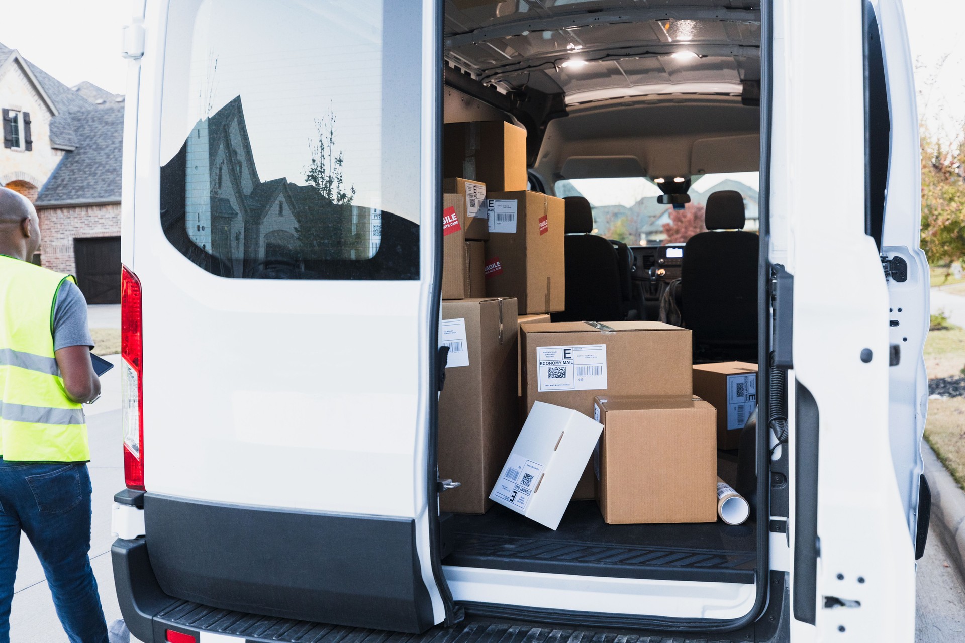 Unrecognizable delivery man walks away from open door of van